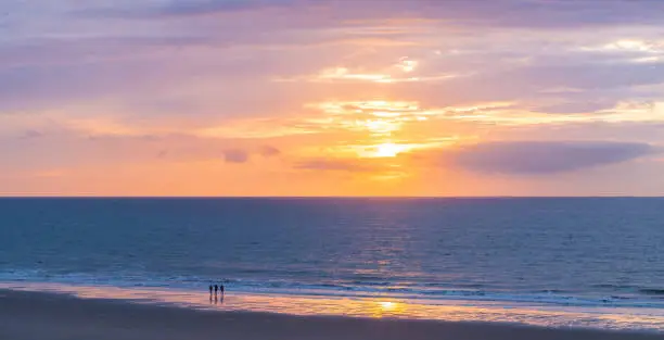 Three people enjoying a North Sea beach sunset, Oostende (Ostend), Belgium.
