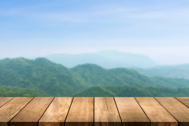 istock Wooden table top with nature mountain and forest blurred background. Copy space for your display or montage product design. 1326956576