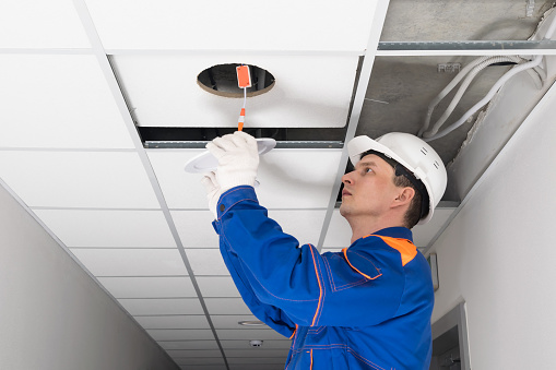 the electrician installs the lighting in the suspended ceiling