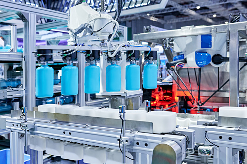 Close-up of robot arm gripping bottles at production line in bottling plant.
