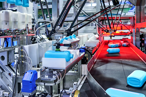 Close-up of robot arm choosing bottles at production line in bottling plant.
