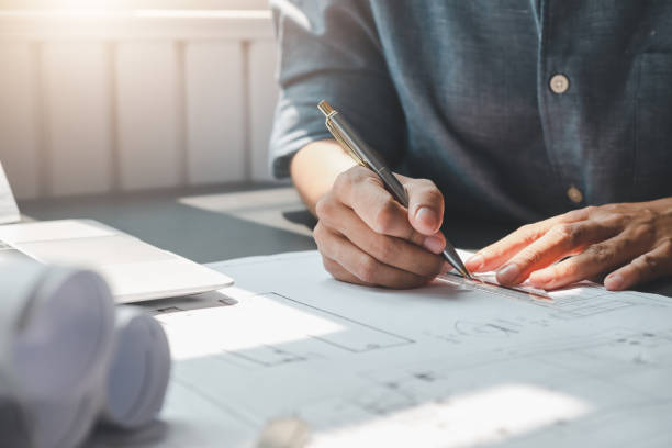 Close-up Man architect hand drafting a building construction drawing at the office.