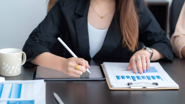 istock Close-up of a young businesswoman hand analyzing  graph taking notes using the tablet at the office. 1326961105