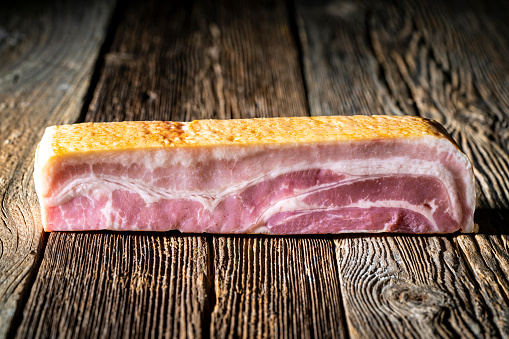Bacon pork meat piece raw or rustic wooden board table wood plank background