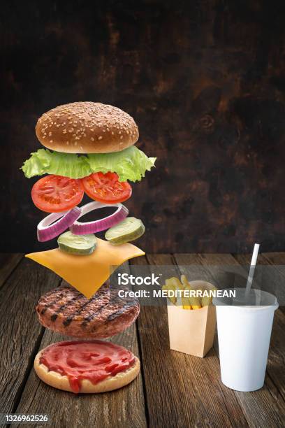 Burger Ingredients Flying With Combo Of French Fries And Disposable Beverage Paper Glass On Dark Wood Stock Photo - Download Image Now