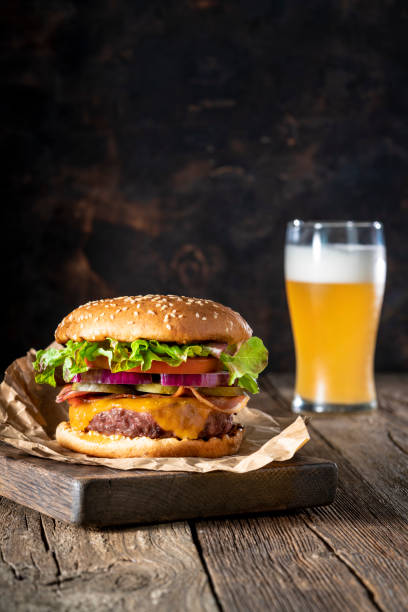 cheeseburger burger patty classic mit biermenü auf rustikalem holzbrett - beer hamburger american culture beef stock-fotos und bilder