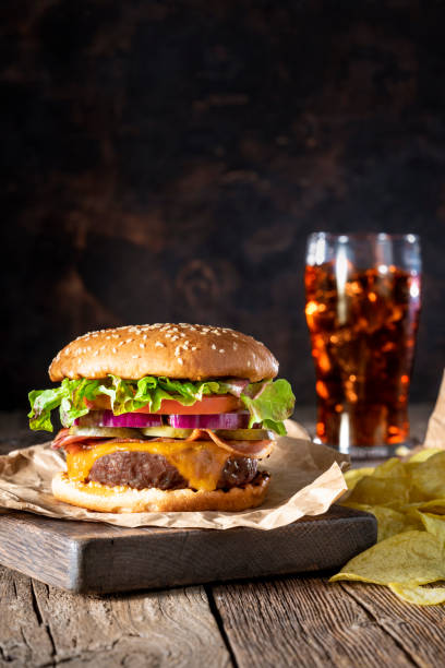 istock Cheeseburger Burger Patty classic with potato chips and cola soda menu on rustic wood table 1326962618
