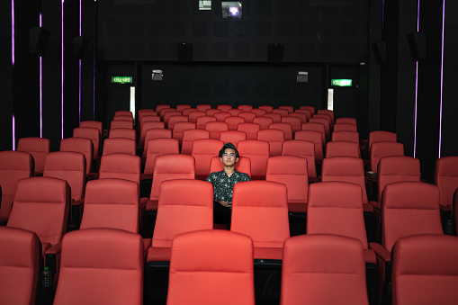 Asian Chinese teenager alone in cinema watching movie