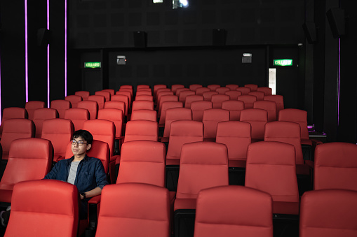 Asian Chinese young man alone in cinema watching movie