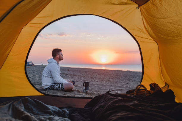 istock man cooking coffee at sea sandy beach. summer camping vacation 1326964764