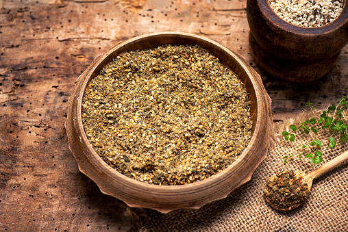 Raw Organic MIddle Eastern Zaatar Spices in a Bow on wooden table tabletop view. Za'atar is a culinary herb or family of herbs. It is also the name of a spice mixture that includes the herb along with toasted sesame seeds, dried sumac and salt