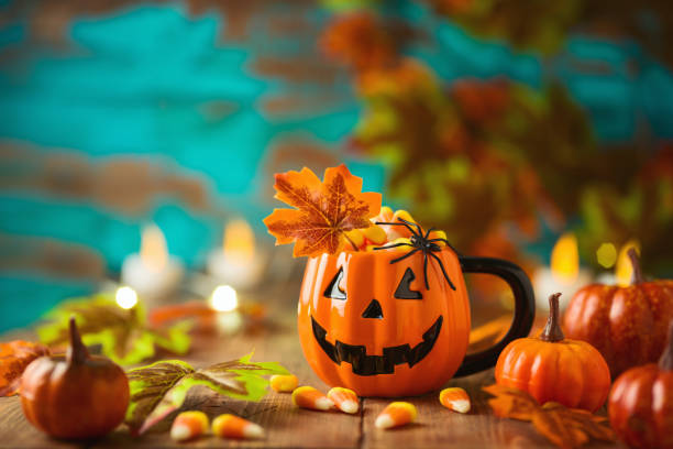 istock Halloween celebration concept with candy corn, jack o lantern cup, pumpkin and autumn leaves. 1326968744