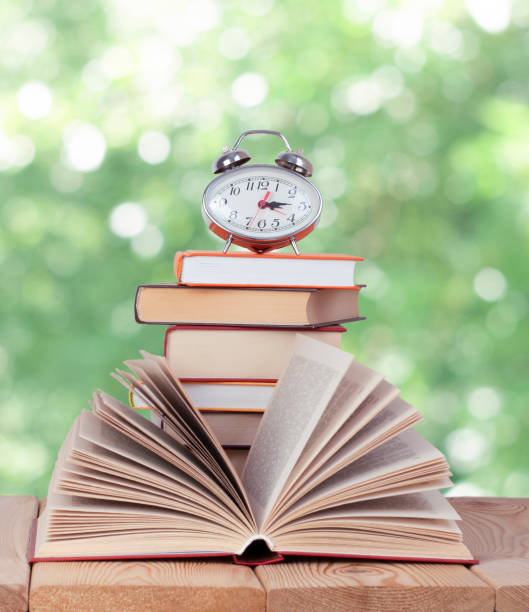 istock Open book with silver watch on the stack of books in the nature 1326974476