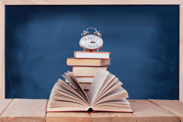 istock Open book with silver watch on the stack of books 1326974477