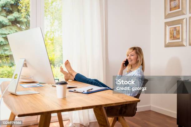 Attractive Middle Aged Woman Sitting At Desk And Working From Home Stock Photo - Download Image Now