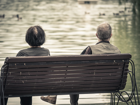 Bucharest, Romania - 06.04.2021:Vintage picture with two seniors sitting on a bench in a park and looking at the lake