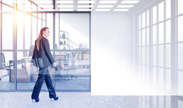 istock Young businesswoman walking along office open space. Double exposure. Workspaces on background. 1326978414