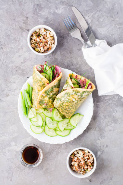 istock Egg rolls filled with pastrami, vegetables and green onions on a plate, sprouted grains and soy sauce in bowls on the table. Hearty and high-calorie snack. Top and vertical view 1326979424
