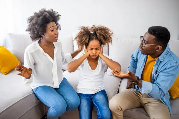 Desperate littlegirl during parents quarrel. Frustrated little girl scared with mom and dad fighting at home, sad stressed child suffers from parents argument or divorce causing mental psychological trauma,