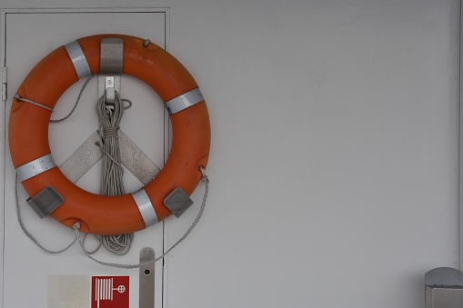 Orange life buoy on the white wall of tourist cruiser vessel with copy space passing Lake Zurich.