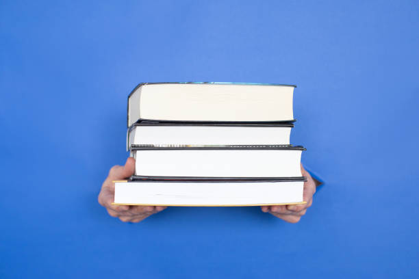 istock Female hands hold books on a blue background. 1326985458