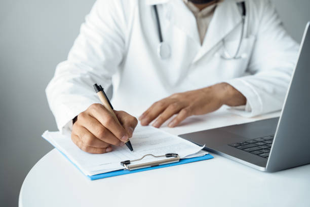 istock Mid-section arabian male doctor hands writing in patient checklist form 1326986530
