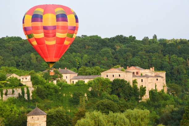istock A large multicolored hot air balloon flies low over ancient buildings and a tree-lined valley. Photographed at close range 1326988418