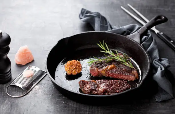 Roasted beef ribeye steak in a cast iron frying pan, a selective focus