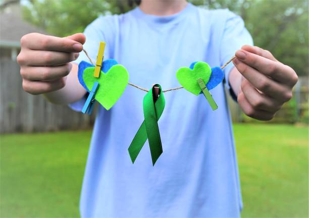 green ribbon, hearts, hands--medical awareness: non-hodgkin lymphoma; mental health - non hodgkin lymphoma imagens e fotografias de stock