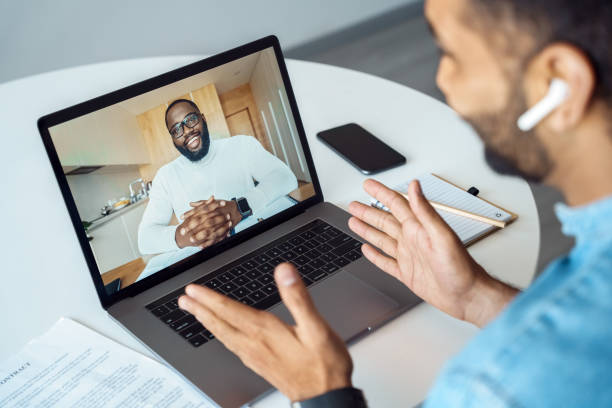 Afro american man talking using webcam internet connection, view over shoulder stock photo