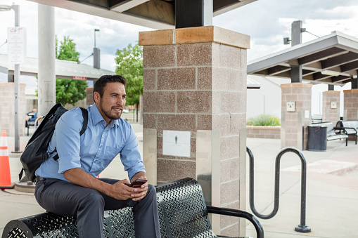 In Western Colorado Millennial Hispanic Male Commuter Waiting for Public Transportation at Bus Stop Photo Series (Shot with Canon 5DS 50.6mp photos professionally retouched - Lightroom / Photoshop - original size 5792 x 8688 downsampled as needed for clarity and select focus used for dramatic effect)