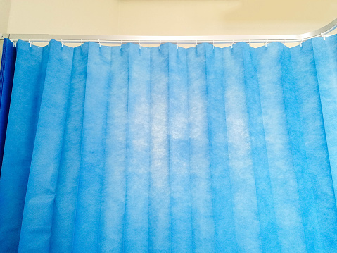 A view from the perspective of a hospital patient. The bed space curtain drawn around to give the patient privacy,