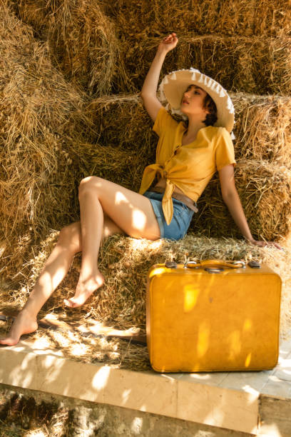 portret kobiety ze słomkowym kapeluszem siedzącym na sianie. - fashion women denim farm zdjęcia i obrazy z banku zdjęć
