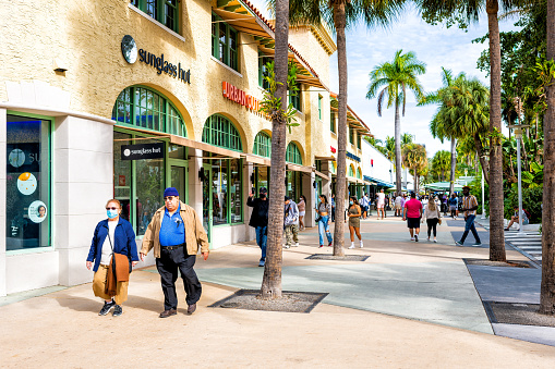 Miami Beach, USA - January 17, 2021: Famous Lincoln road shopping street with people walking by stores shops Sunglass Hut retail on sunny winter day