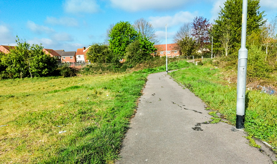 A path leading through some waste ground connecting two areas of properties.