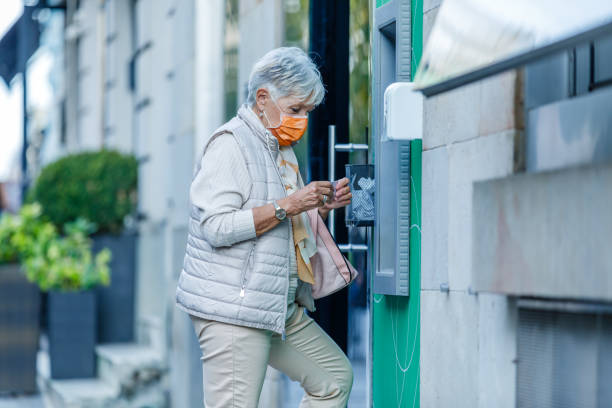istock An Older Woman with Face Mask is Using ATM. 1327004742