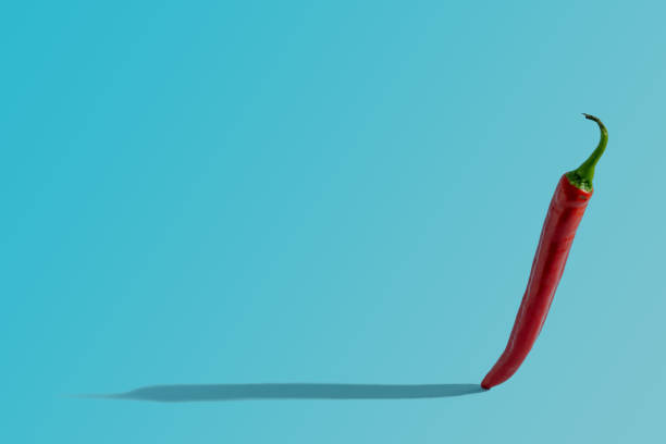 istock Standing red pepperoni on pastel blue background. Shadow on the left. Creative food concept 1327006268