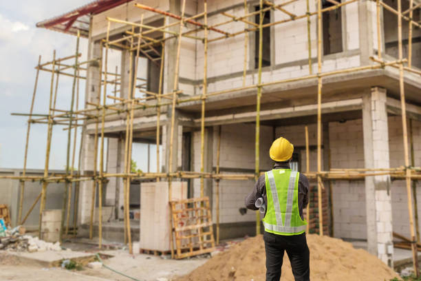 istock young professional engineer in protective helmet and blueprints paper at the house building construction site 1327007725