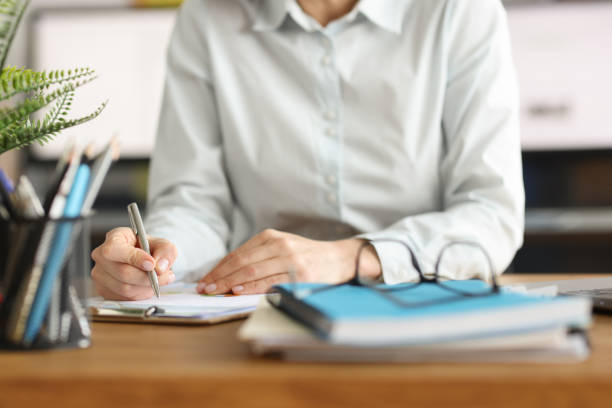 mujer escribe con lápiz en documentos en el lugar de trabajo - secretary fotografías e imágenes de stock