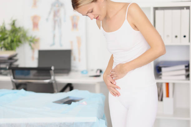 Young woman with abdominal pain in medical office Young woman with abdominal pain in medical office. Menstrual pain in the lower abdomen concept Cushing Syndrome stock pictures, royalty-free photos & images