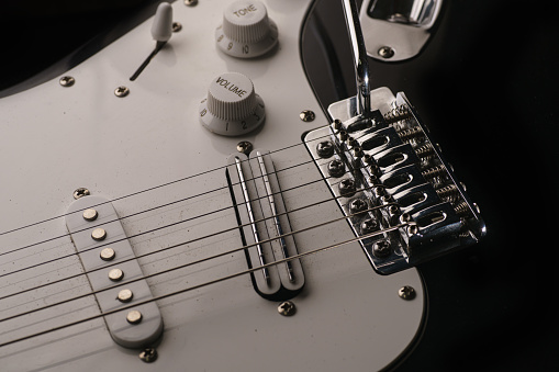 Black and white electronic guitar close up view. Details of rock guitar. Strings, tremolo and volume control.