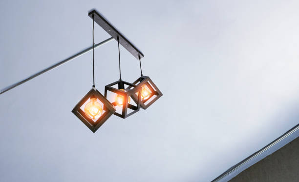 istock Illuminated modern three metal cage hanging lamps with electrical conduit pipes on white ceiling inside of living room 1327023099