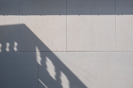 Sunlight and balcony shadow on surface of gray gypsum wall background