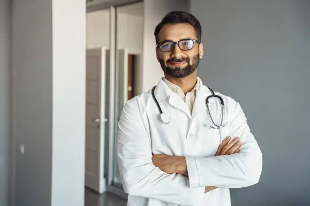 Photo of Portrait of male doctor in white coat and stethoscope standing in clinic hall