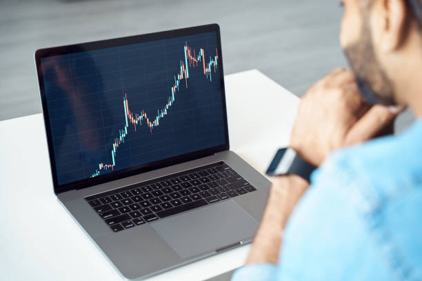 istock Indian man waiting looking at laptop screen with financial graph chart 1327027003