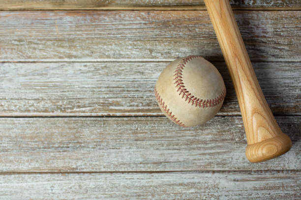 TD worn baseball, bat A top down view of a worn baseball and the bottom handle portion of a wooden baseball bat on a wooden surface, as a background image. baseball bat home run baseball wood stock pictures, royalty-free photos & images