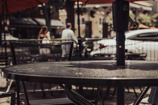 A black metal table outside a restaurant in a town as women walk by in the background.