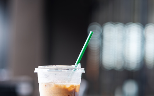Closeup image of a plastic glass of iced coffee with straw
