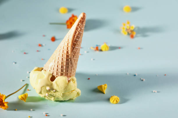 istock Orange ice cream with waffle cone on blue background with yellow flowers 1327036652