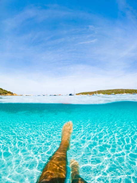 (foco seletivo) vista deslumbrante de uma pessoa nadando em uma água turquesa e clara. metade do mar subaquático e metade azul imagem do céu. arquipélago la maddalena, sardenha, itália. - below sea level - fotografias e filmes do acervo